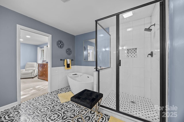 bathroom featuring a stall shower, a freestanding tub, wainscoting, and tile walls