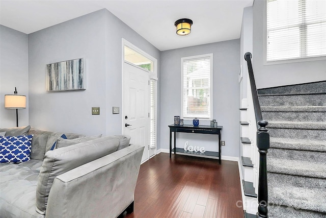 foyer entrance featuring dark wood-style flooring, stairway, and baseboards