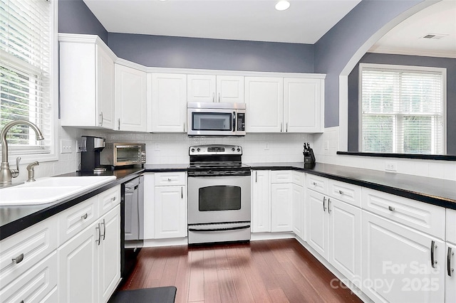 kitchen featuring stainless steel appliances, a sink, dark wood finished floors, white cabinets, and recessed lighting