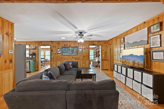 909 Pearson Falls Rd, Saluda, NC 28773 - living room with wood walls, healthy amount of natural light, a ceiling fan, and light wood-style flooring