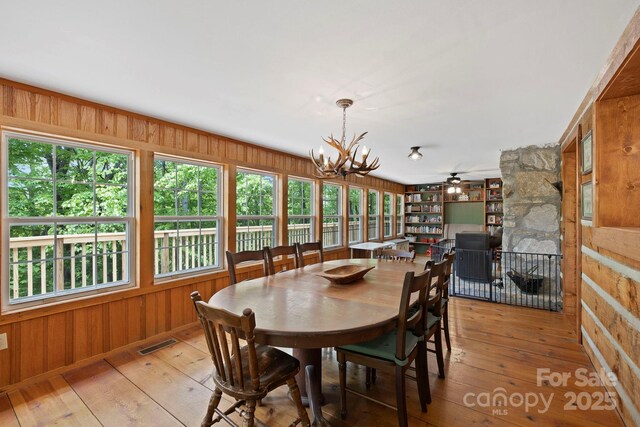 909 Pearson Falls Rd, Saluda, NC 28773 - dining area featuring healthy amount of natural light, wood walls, light wood-type flooring, and a chandelier