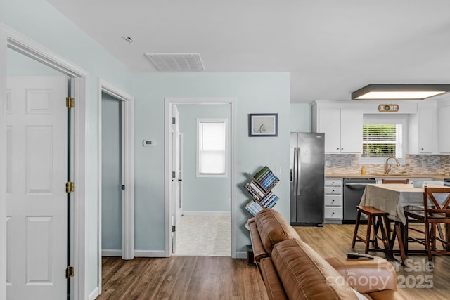 772 Austin Rd, New London, NC 28127 - kitchen with appliances with stainless steel finishes, light wood-type flooring, light countertops, white cabinets, and backsplash