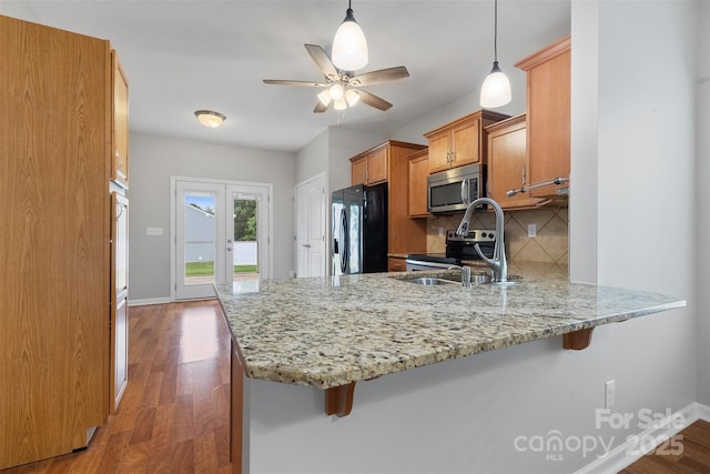 5076 Newport Lakes Dr, Rock Hill, SC 29732 - kitchen featuring stainless steel appliances, a peninsula, brown cabinets, tasteful backsplash, and baseboards