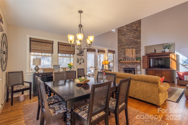 196 Juneberry Ln, Tuckasegee, NC 28783 - dining space featuring a chandelier, light wood finished floors, a fireplace, high vaulted ceiling, and baseboards
