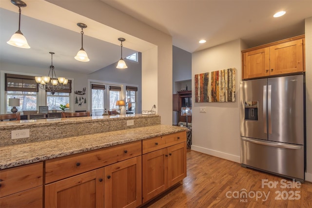 196 Juneberry Ln, Tuckasegee, NC 28783 - kitchen with stainless steel fridge, vaulted ceiling, light wood-style flooring, light stone counters, and hanging light fixtures