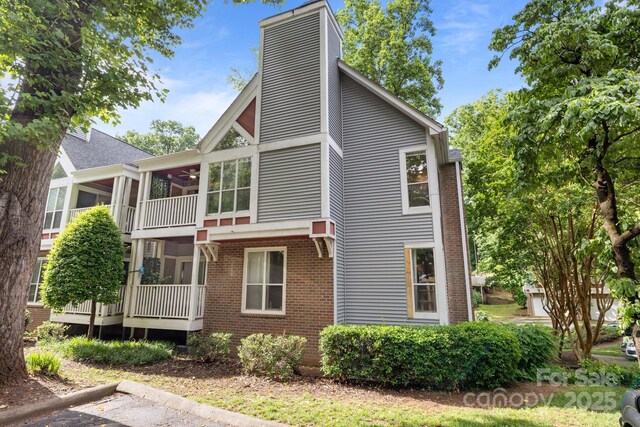 2502 Cranbrook Ln Unit 8, Charlotte, NC 28207 - view of side of property with a chimney, brick siding, a sunroom, and uncovered parking