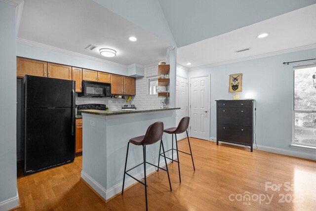 2502 Cranbrook Ln Unit 8, Charlotte, NC 28207 - kitchen featuring black appliances, dark countertops, tasteful backsplash, ornamental molding, and a kitchen bar