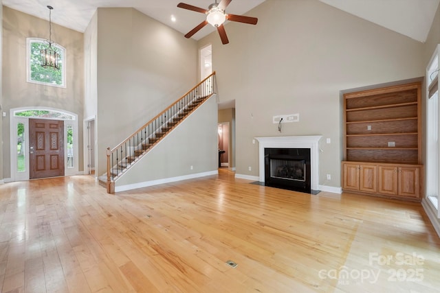 8216 Malibu Pointe Ln, Denver, NC 28037 - unfurnished living room with a high ceiling, stairs, wood-type flooring, a chandelier, and a ceiling fan
