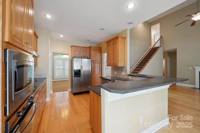 8216 Malibu Pointe Ln, Denver, NC 28037 - kitchen with stainless steel fridge, a peninsula, dark countertops, a ceiling fan, and decorative backsplash