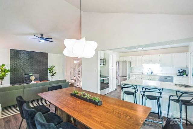 52 Reynolda Dr, Asheville, NC 28803 - dining space with stairs, dark wood finished floors, a brick fireplace, ceiling fan, and high vaulted ceiling