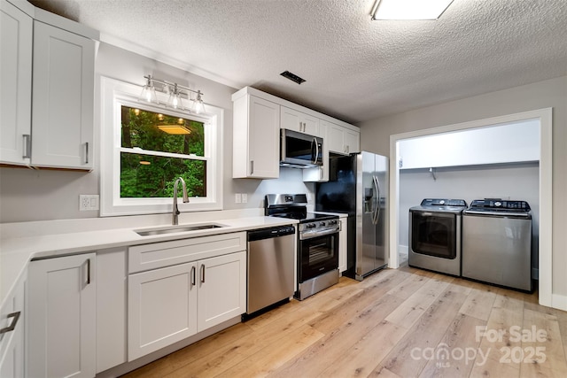 16 Arkansas Trl, Cullowhee, NC 28723 - kitchen featuring washing machine and clothes dryer, appliances with stainless steel finishes, a sink, light wood finished floors, and light countertops