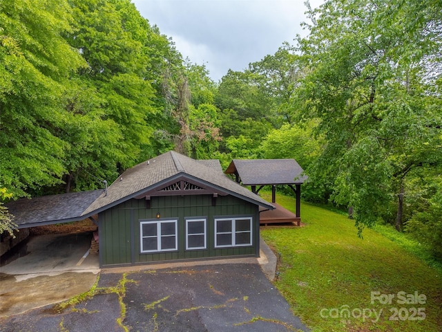 16 Arkansas Trl, Cullowhee, NC 28723 - view of front of property featuring board and batten siding, asphalt driveway, roof with shingles, a front yard, and a wooded view