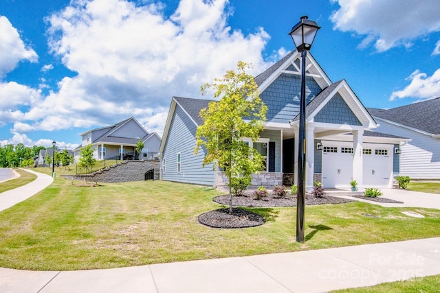 view of front of home with a garage, a front lawn, concrete driveway, covered porch, and stone siding