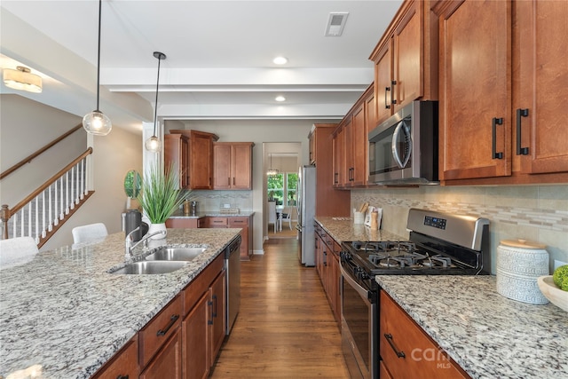 3211 Gilroy Dr, Fort Mill, SC 29707 - kitchen featuring appliances with stainless steel finishes, a sink, brown cabinets, dark wood-style flooring, and light stone counters