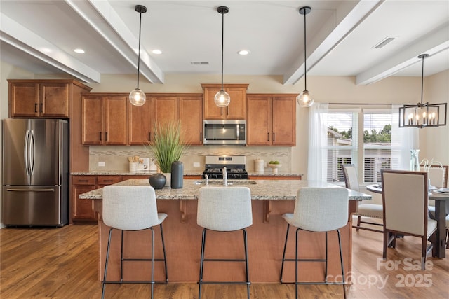 3211 Gilroy Dr, Fort Mill, SC 29707 - kitchen featuring appliances with stainless steel finishes, brown cabinetry, beamed ceiling, tasteful backsplash, and hanging light fixtures