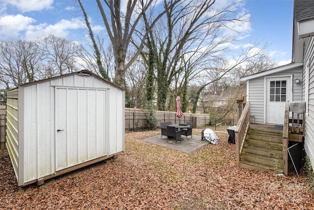 fenced backyard featuring a storage unit, an outbuilding, and a patio area