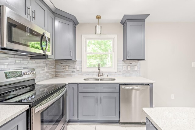 kitchen featuring appliances with stainless steel finishes, a sink, gray cabinets, and backsplash