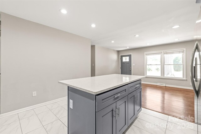 kitchen featuring gray cabinetry, recessed lighting, a center island, baseboards, and light tile patterned floors