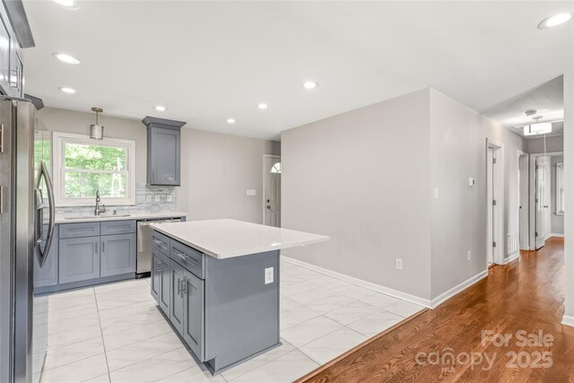 kitchen with appliances with stainless steel finishes, a sink, gray cabinetry, light countertops, and recessed lighting