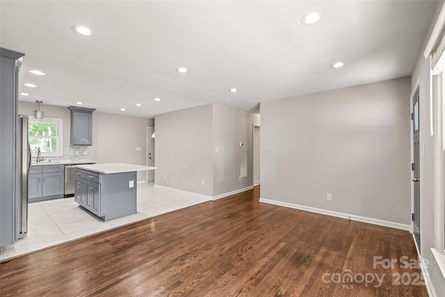 kitchen with gray cabinets, a center island, light wood finished floors, stainless steel appliances, and recessed lighting