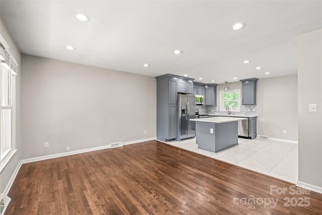 kitchen featuring stainless steel appliances, gray cabinets, light countertops, a center island, and recessed lighting