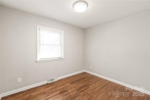 spare room with baseboards and dark wood-style flooring