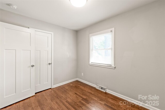 unfurnished bedroom with dark wood-type flooring and baseboards