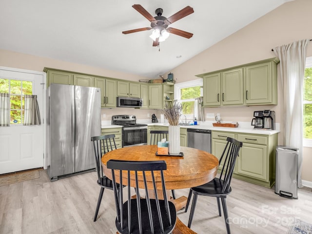 kitchen with green cabinets, stainless steel appliances, lofted ceiling, and light wood-style flooring
