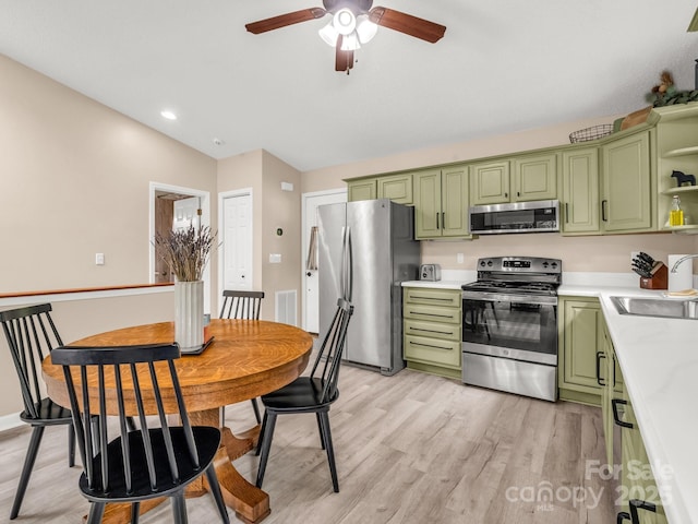 kitchen with green cabinets, stainless steel appliances, a sink, light countertops, and open shelves