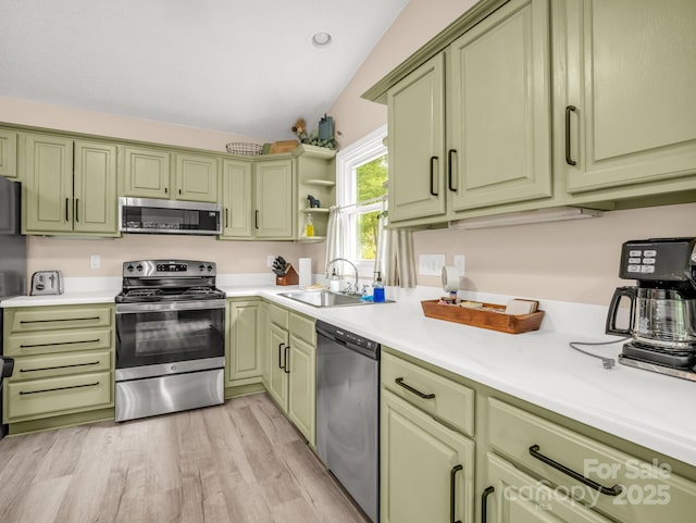 kitchen with stainless steel appliances, green cabinetry, a sink, and vaulted ceiling