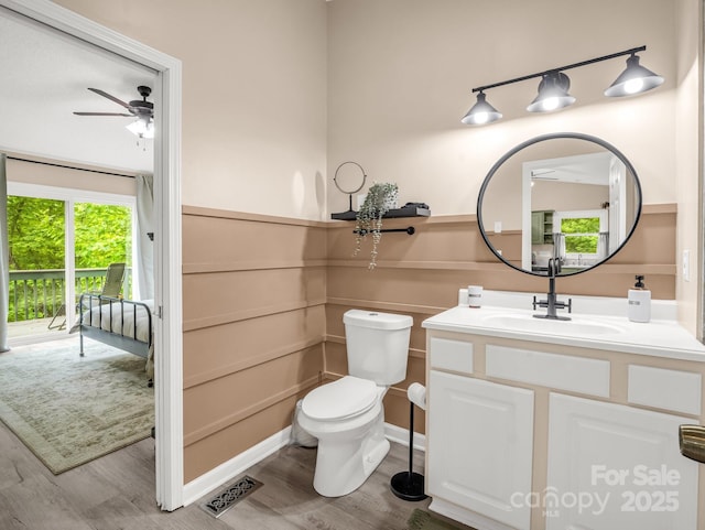 half bathroom featuring wood finished floors, a ceiling fan, vanity, and toilet