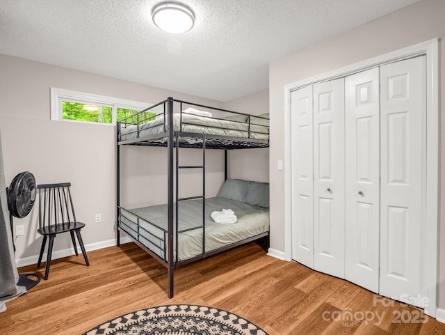 bedroom featuring wood finished floors, a closet, a textured ceiling, and baseboards
