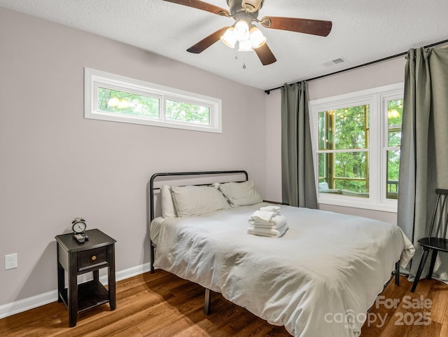 bedroom featuring wood finished floors, a ceiling fan, a textured ceiling, and baseboards