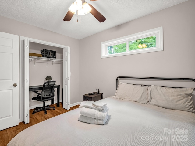 bedroom with wood finished floors, a closet, ceiling fan, and baseboards