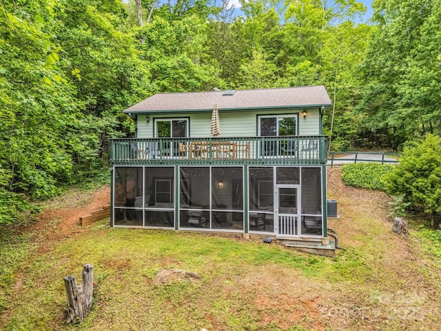 back of house featuring a sunroom, a lawn, and central AC