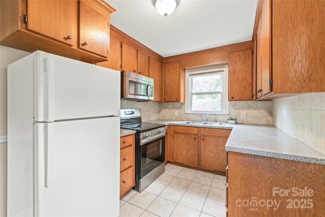 104 Willetta Dr, Charlotte, NC 28217 - kitchen featuring appliances with stainless steel finishes, a sink, brown cabinets, decorative backsplash, and light countertops
