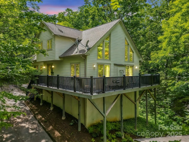 rear view of property with a deck and a shingled roof