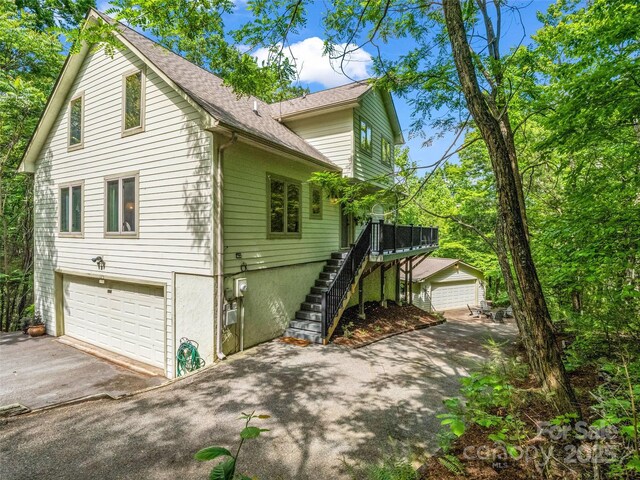 view of home's exterior featuring asphalt driveway, stairway, an attached garage, and a shingled roof