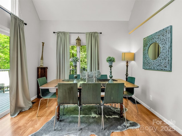 dining area featuring vaulted ceiling, baseboards, and wood finished floors