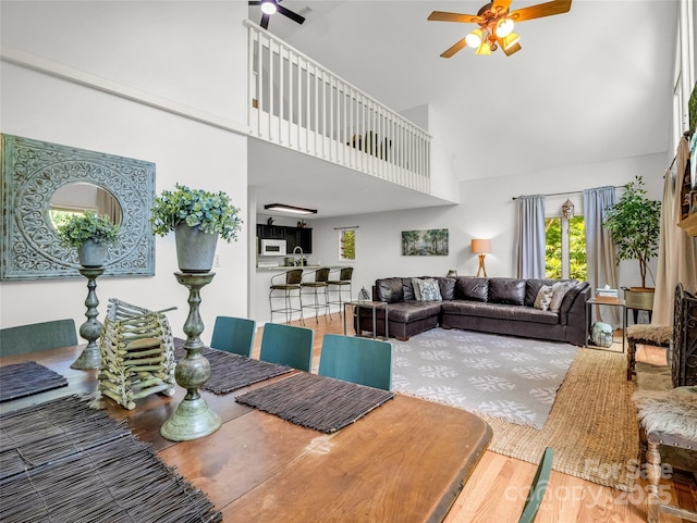 living room with ceiling fan, high vaulted ceiling, and wood finished floors