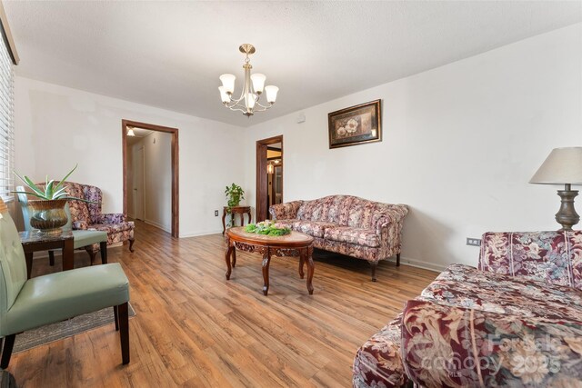 living area featuring a chandelier, light wood-style floors, and baseboards