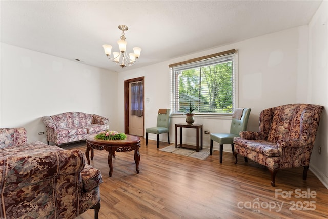 living room with a chandelier, light wood-style floors, and baseboards