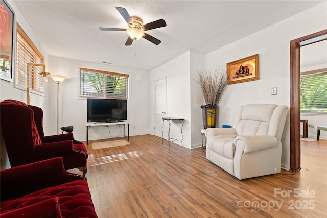 living area with wood finished floors, ceiling fan, and baseboards