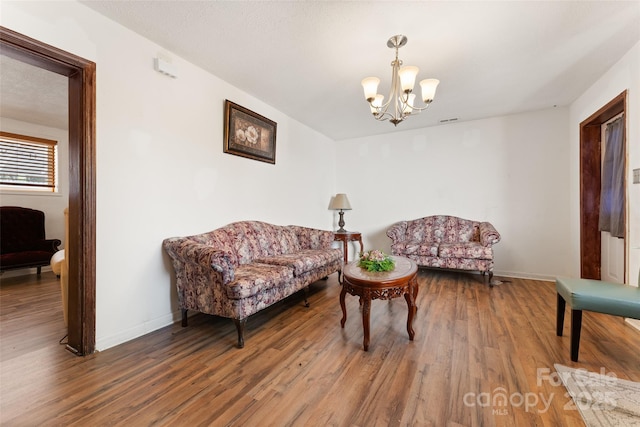 living area featuring wood finished floors, a chandelier, and baseboards