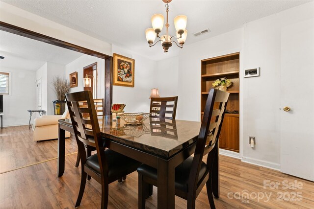 dining area featuring a chandelier, wood finished floors, and baseboards