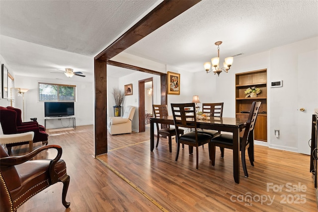 dining space featuring light wood finished floors, a chandelier, a textured ceiling, ceiling fan, and built in features