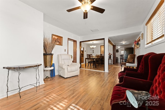 living area with ceiling fan, wood finished floors, and a chandelier