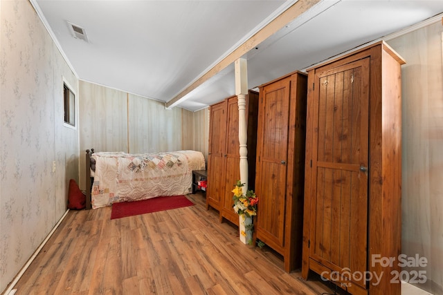 bedroom featuring wood finished floors and wallpapered walls