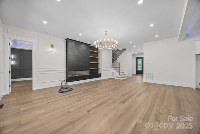 1408 Bloomsberry Ln, Waxhaw, NC 28173 - unfurnished living room with a decorative wall, stairway, a fireplace, recessed lighting, and light wood-style floors
