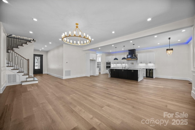 1408 Bloomsberry Ln, Waxhaw, NC 28173 - unfurnished living room featuring a chandelier, light wood-style flooring, baseboards, recessed lighting, and a sink